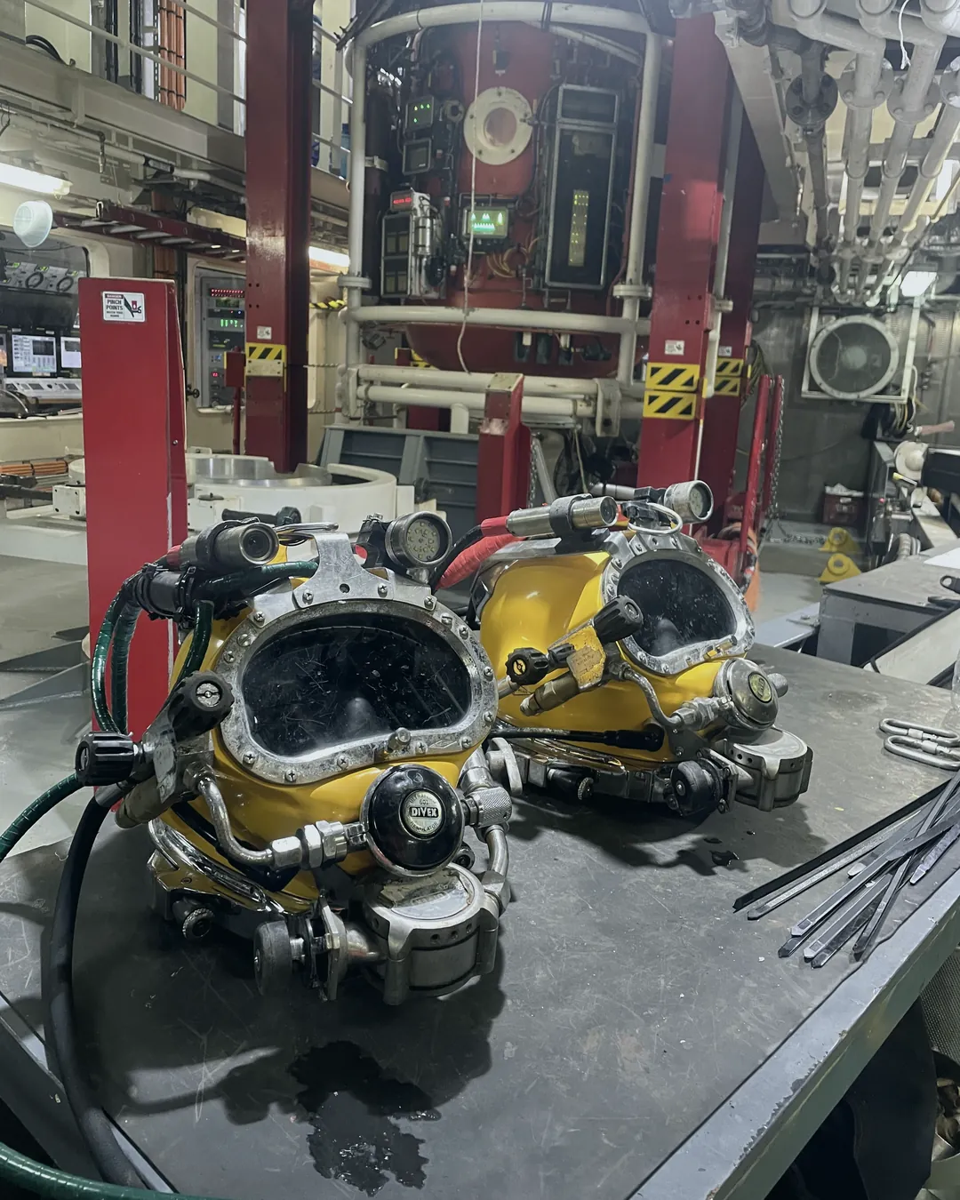 Two yellow KM dive helmets on a bench in a dive support vessel's dive station